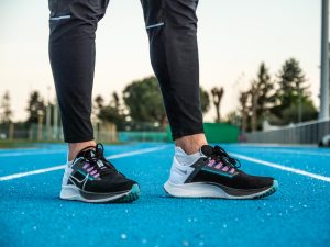 Paire de chaussure Nike Zoom Pegasus 38 portées au pieds de Benjamin Robert, sur une piste d'athlétisme en tartan bleu.