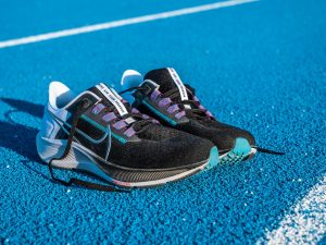 Zoom sur une paire de chaussure Nike Zoom Pegasus 38 posées sur le sol, sur une piste d'athlétisme en tartan bleu.