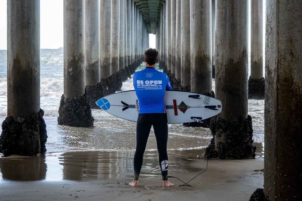 Gaspard Larsonneur de dos, face à l'océan, sour le Pier de Huntington Beach en Californie, pendant l'US Open of Surfing 2022
