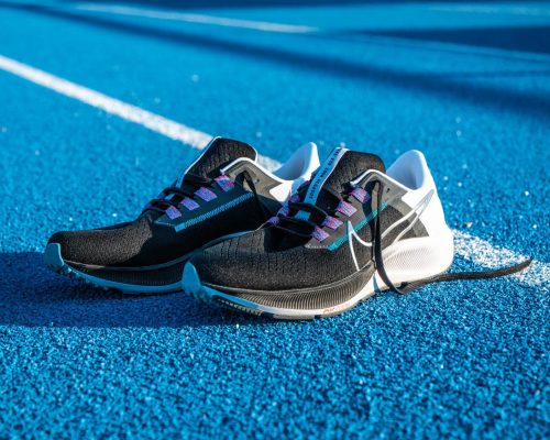 Zoom sur une paire de chaussure Nike Zoom Pegasus 38 posées sur le sol, sur une piste d'athlétisme en tartan bleu.